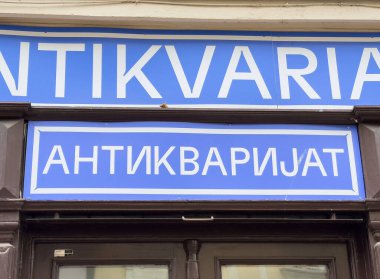 Ljubljana, Slovenya - Temmuz 06, 2025: Antika mağazası işareti Kiril alfabesindeki 'Antivarijat' sözcüğünü vurgulayan mavi arkaplan ve beyaz metne sahip
