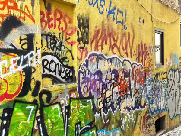 Ljubljana, Slovenya - 06 Temmuz 2025: Canlı grafiti sanatı, kentte kentsel kültürü yansıtan çeşitli renkler ve sanatsal stillerin yer aldığı sarı bir duvarı süslüyor