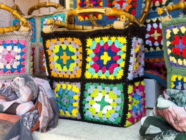 Burano, İtalya - 25 Haziran 2025: El yapımı örgü çantası, diğer zanaatkârlık ve kültür sanatları ile birlikte sergilenen canlı desenler ve renkler içeriyor