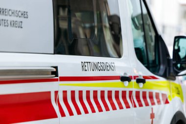 Villach, Avusturya - 11 Temmuz 2025: Sokağa park etmiş kırmızı ve sarı çizgili acil ambulans, kurtarma hizmetleri ve kentsel ayar