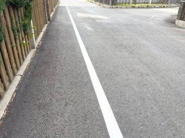 Güneşli bir günde kaldırımlı ve çitli sakin bir sokak köşesi..