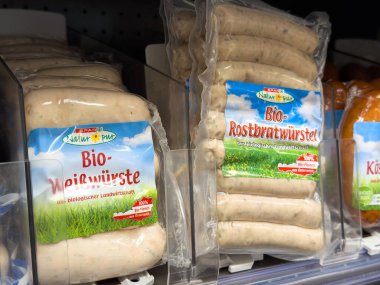 Villach, Avusturya - 10 Temmuz 2025: Süpermarkette organik beyaz ve ızgara sosisler, çevre dostu paketler ve sağlıklı alışverişçiler için taze malzemeler vurgulanıyor