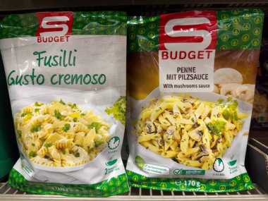 Villach, Avusturya - 10 Temmuz 2025: S Bütçeli makarna ürünleri arasında Fusilli Gusto Cremoso ve Penne mit Pilzsauce ve mantar mantarlı market rafları yer alıyor