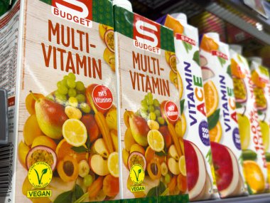 Villach, Avusturya - 10 Temmuz 2025: S-Budget multi-vitamin meyve suyu kutuları renkli meyve çizimleri ve vegan etiketlerinin yer aldığı bir süpermarket rafında düzenlenmiştir.