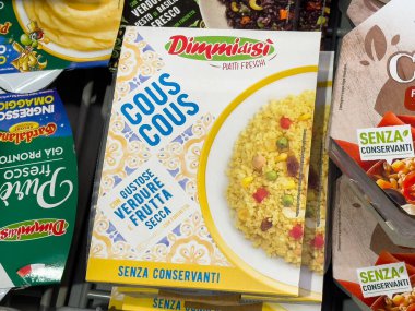 Villach, Avusturya - 10 Temmuz 2025: Market rafındaki Dimdimasi kuskus kutusu, renkli tahıllar ve sağlıklı yemek hazırlığı için taze malzemeler vurgulanıyor