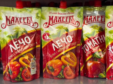 Villach, Avusturya - 15 Temmuz 2025: Taze sebzeler ve marka logosunun ön plana çıkarıldığı bir rafta parlak renkli leço ve domates sosları sergileniyor