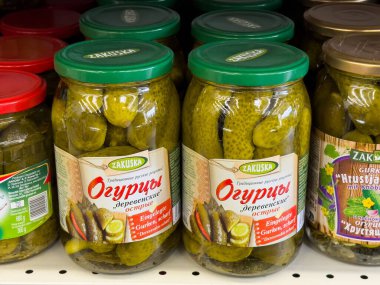 Villach, Avusturya - 15 Temmuz 2025: Market rafındaki kavanozlarda turşu markası, parlak yeşil salatalıklar ve renkli kapaklar, yemek severler için mükemmel