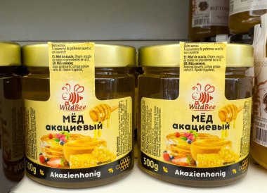 Villach, Avusturya - 15 Temmuz 2025: Yabanarısı akasya kavanozları çekici etiketlerini ve doğal malzemelerini ön plana çıkaran bir rafta sergileniyor
