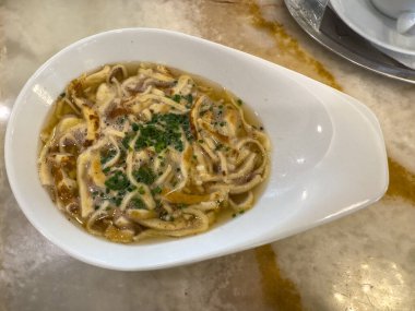 Geleneksel Avusturyalı frittatensuppe mermer masa üzerinde beyaz bir kase.