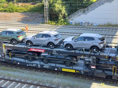 Arnoldstein, Avusturya - 20 Temmuz 2025: Elektrikli cipler, yenilikçi otomotiv tasarımı ve verimli ulaşımı ön plana çıkaran bir nakliye trenine güvenli bir şekilde yüklendi