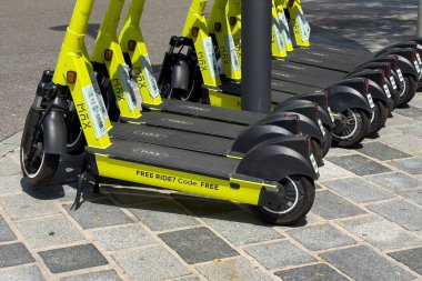 Villach, Avusturya - 24 Temmuz 2025: Sarı elektrikli scooterlar şehir kaldırımına park edilmiş, yenilikçi kentsel hareketlilik çözümleri ve tanıtım teklifleri vurgulanıyor