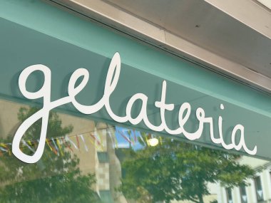 Villach, Avusturya - 24 Temmuz 2025: Dükkan vitrininde Gelateria tabelası zarif senaryo ve renkli dekorasyonlar içeriyor, müşterileri dondurma yemeye davet ediyor