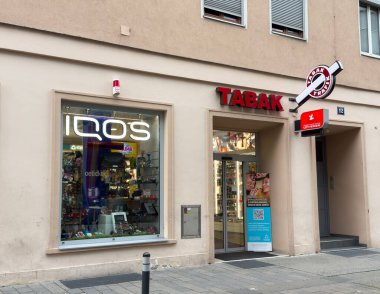 Villach, Avusturya - 24 Temmuz 2025: IQOS ürünleri ve TABAK tabelaları, canlı kentsel bir ortamda yer alarak potansiyel müşterileri cezbediyor
