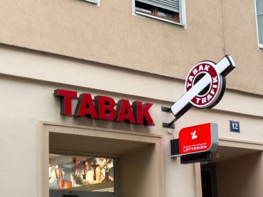 Villach, Avusturya - 24 Temmuz 2025: TABAK mağazası önünde cesur bir tabela ve piyango sergisi yer alıyor, müşteriler için kentsel bir ortam yaratıyor