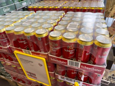 Villach, Avusturya - 24 Temmuz 2025: Schwechater bira kutuları renkli ambalaj ve davetkar atmosferi vurgulayan bir perakende satış ortamında düzenlenmiştir