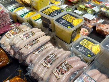 Villach, Avusturya - 24 Temmuz 2025: Paketlenmiş sosisler ve baharatlar, çeşitli aromalar ve dokuların ön plana çıkarıldığı market raflarında düzgünce düzenlenmiştir