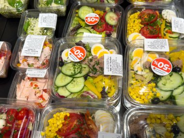 Villach, Avusturya - 24 Temmuz 2025: İndirim etiketli temiz kaplarda taze salatalar, canlı sebzeler ve market ortamında sağlıklı beslenme seçenekleri