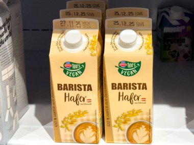 Villach, Avusturya - 24 Temmuz 2025: Kahve meraklıları ve sağlık bilinci olan tüketiciler için vejetaryen içecek tercihlerinin altını çizerek rafa dizilmiş yulaf ezmeli süt kutuları