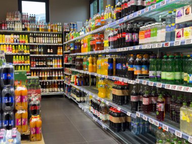 Villach, Avusturya - 24 Temmuz 2025: Çeşitli meşrubat ve meyve sularıyla dolu süpermarket içecek reyonu, canlı ambalajlar ve düzenli düzenlenmiş raflar