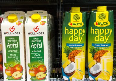 Villach, Avusturya - 24 Temmuz 2025: Hollinger elma suyu ve Rauch mutlu gün hindistan cevizi ananas suyu süpermarket raflarında renklendirilmiş ambalaj ve ürün cazibesini ön plana çıkararak düzenlenir