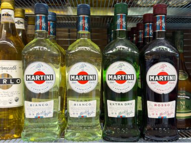 Villach, Avusturya - 24 Temmuz 2025: Bianco, Extra Dry ve Rosso da dahil olmak üzere Martini şişeleri, bir içki dükkanının rafında düzenli bir şekilde düzenlenmiştir.