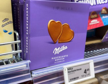 Villach, Avusturya - 24 Temmuz 2025: Milka çikolata kutusu süpermarket raflarında kalp şeklinde şekerler sergileniyor, renkli ambalajlar ve çekici tasarımlar vurgulanıyor