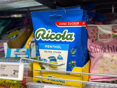 Villach, Avusturya - 24 Temmuz 2025: Ricola mentollü şeker paketi bir süpermarket rafında belirgin bir şekilde sergileniyor, şekersiz faydaları ve çekici tasarımı vurgulanıyor