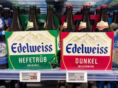 Villach, Avusturya - 24 Temmuz 2025: Edelweiss bira şişeleri, Hefeweibier ve Dunkel, renkli ambalajlı bir süpermarket rafında sergilenmektedir