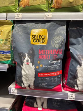 Villach, Avusturya - 24 Temmuz 2025: Mağaza rafındaki altın renkli orta boy köpek maması paketini seçin, prim malzemelerini vurgulayın ve evcil hayvan sahipleri için çekici tasarım
