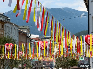 Villach, Avusturya - 24 Temmuz 2025: Vibrant kırmızı ve sarı kurdeleler Villach sokaklarında asılı, 80. Geleneksel Köy Kirchtag Festivali 'ni kutluyorlar
