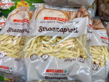 Tarvisio, İtalya - 26 Temmuz 2025: Despar Strozzapreti makarna paketleri lezzetli yemekler için taze malzemelerin altını çizerek bir süpermarket rafına düzgünce yerleştirilmiştir