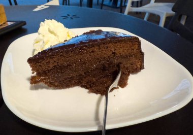 Beyaz tabakta krem şantili lezzetli çikolatalı pasta dilimi..