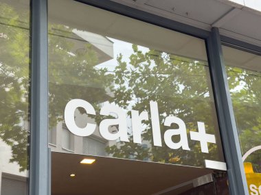 Villach, Avusturya - 28 Temmuz 2025: Carla + mağaza tabelası şehir ortamında geniş cam pencereli ve yemyeşil renkli çağdaş tasarım içeriyor