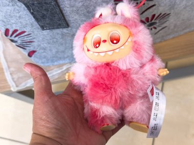 Villach, Avusturya - 28 Temmuz 2025: Pembe kürklü ve neşeli ifadeli renkli pelüş bir oyuncak, çocuklar için mükemmel ve eğlenceli bir dekor