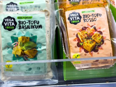 Villach, Avusturya - 28 Temmuz 2025: Fesleğen ve kırmızı aromalı vejetaryen tofu ürünleri, bitki temelli seçenekleri ön plana çıkaran bir markette sergilenmektedir