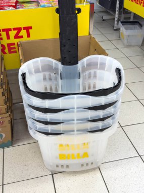 Villach, Avusturya - 28 Temmuz 2025: Market koridorunda yığılmış şeffaf alışveriş sepetleri, alışveriş için pratik tasarım ve hizmetlerini ön plana çıkarıyor