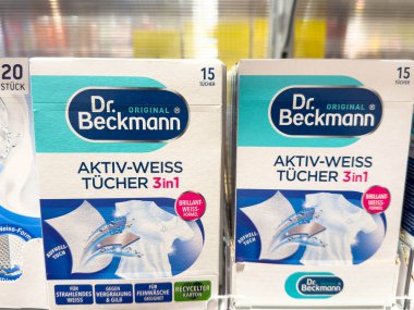 Villach, Avusturya - 28 Temmuz 2025: Dr. Beckmann Aktiv-Weiss etkili temizlik için canlı renkleri ve ürün detaylarını vurgulayarak raftaki paketleri temizliyor