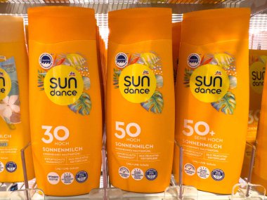 Villach, Avusturya - 28 Temmuz 2025: Güneş Dansı güneş kremi ürünleri farklı SPF seviyeleri ve güneş koruması için parlak sarı ambalajlar içeren bir rafa dizildi