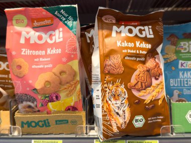 Villach, Avusturya - 28 Temmuz 2025: Limon ve kakao aromalı parlak renkli Mogli kurabiye paketleri bir süpermarketin rafında, organik cazibelerini vurgulayarak düzenlenmiştir