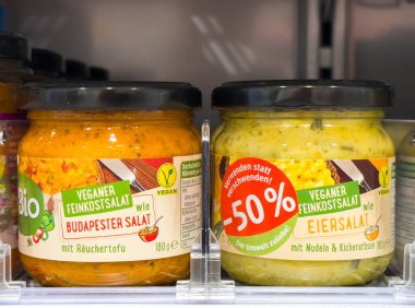 Villach, Avusturya - 28 Temmuz 2025: Süpermarket raflarındaki kavanozlarda vejetaryen gurme salataları, Budapeşte ve yumurta salatası alternatifleri sergileniyor parlak renklerle ve çekici etiketlerle