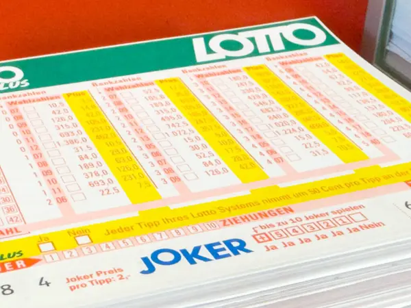 Villach, Avusturya - 28 Temmuz 2025: Piyango bileti, piyango katılımının ve şans oyununun heyecanını gözler önüne seren canlı sayılar ve ızgaralar içeren bir masa.