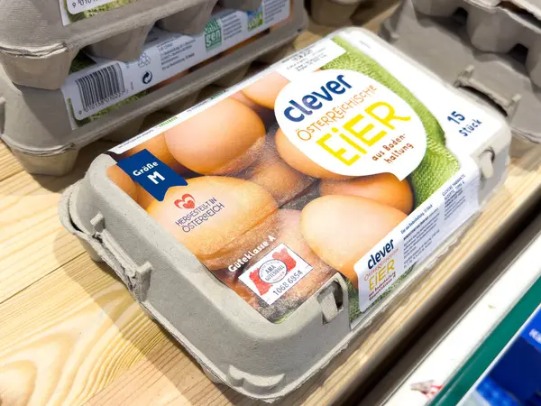 Villach, Avusturya - 28 Temmuz 2025: 15 yumurtalı akıllı yumurta kutusu, marketteki ahşap rafta, taze organik ürünlerin altını çizerek belirgin bir şekilde sergileniyor