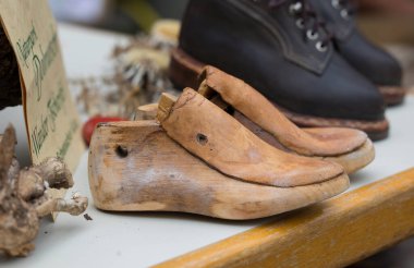 Villach, Avusturya - 28 Temmuz 2025: Ahşap ayakkabılar Jakobimarkt 'taki bir masanın üzerinde geleneksel ayakkabı yapma metodlarının sanatını vurgulayarak belirgin bir şekilde yer alır.