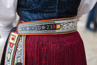 Villach, Avusturya - 28 Temmuz 2025: Detaylı nakış ve renkli kuşakla geleneksel halk kıyafetleri, canlı renklerde kültürel önemi ve zanaatkarlığı vurguluyor