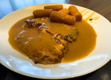 Lezzetli soslu domuz bifteği ve beyaz tabakta kızarmış atıştırmalıklar..