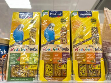 Villach, Avusturya - 30 Temmuz 2025: Vitakraft Kracker Kuş maması paketleri, canlı renkler ve mavi bir muhabbet kuşu grafiği sergilenen bir rafta sergilenmektedir