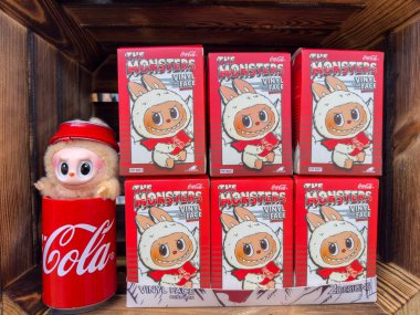 Villach, Avusturya - 30 Temmuz 2025: Coca-Cola temalı peluş oyuncağın koleksiyon halinde sunumu, eğlenceli karakter tasarımları ve parlak renklerin vurgulandığı Vinil Yüz kutuları