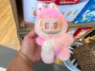 Villach, Avusturya - 30 Temmuz 2025: Pembe ve beyaz kürklü sevimli pelüş oyuncak, büyük gözler ve tüylü doku, canlı bir mağaza ortamında el ele tutuştu