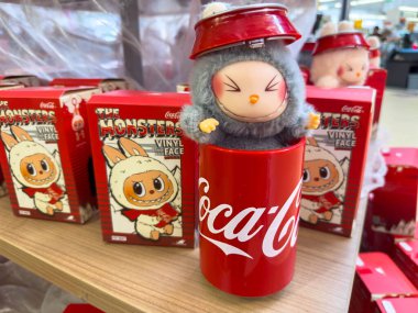 Villach, Avusturya - 30 Temmuz 2025: Sevimli Coca-Cola karakteri kırmızı bardakta, canlı vinil oyuncaklarla çevrili, neşeli bir tatil atmosferi yaratıyor.