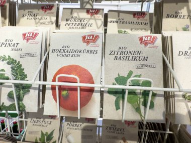 Villach, Avusturya - 30 Temmuz 2025: Sergi rafına dizilmiş tohum paketleri, sürdürülebilir seçenekler arayan bahçıvan aşıklar için ideal organik sebze ve otları ön plana çıkarıyor